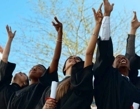 Goodbye college, hello career. Shot of a group of young students throwing their hats in the air on graduation day.
